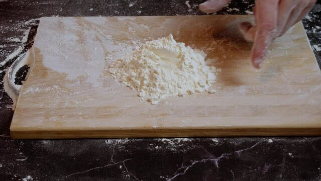 adding flour with a poon to make pizza dough
