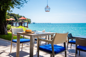 Table in tropical restaurant and beach with turquoise water. Restaurant in luxury resort by the sea. Summer vacation.