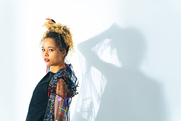 Fashion portrait of a black woman in a fashionable outfit shot in a studio with colorful lighting.