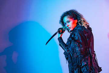 A fashion portrait of a black woman with a Japanese sword shot in a studio with colorful lighting....
