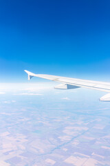 Aerial view from airplane window above green ground. View from the airplane window with beautiful clouds at sunrise