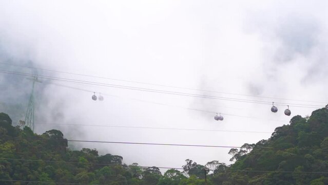 Cable cars in jungle passing through dense clouds in slow motion
