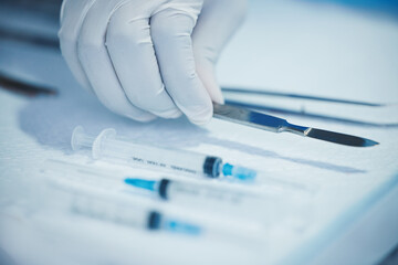 Closeup of hand, doctor and medical tools, scalpel and needle syringe for surgical procedure in...