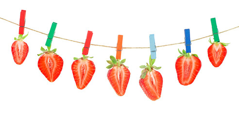 Garland of red ripe strawberries hanging on wooden clothespins on rope, white background.