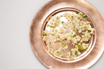 Pretty Feminine Flatlay of Rose Gold Metallic plate of sweet white flowers