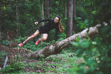 Healthy young woman running on mountain trail at morning tropical forest trail	

