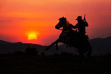 Silhouette of cowboy on horseback and sunset as background - 608909061