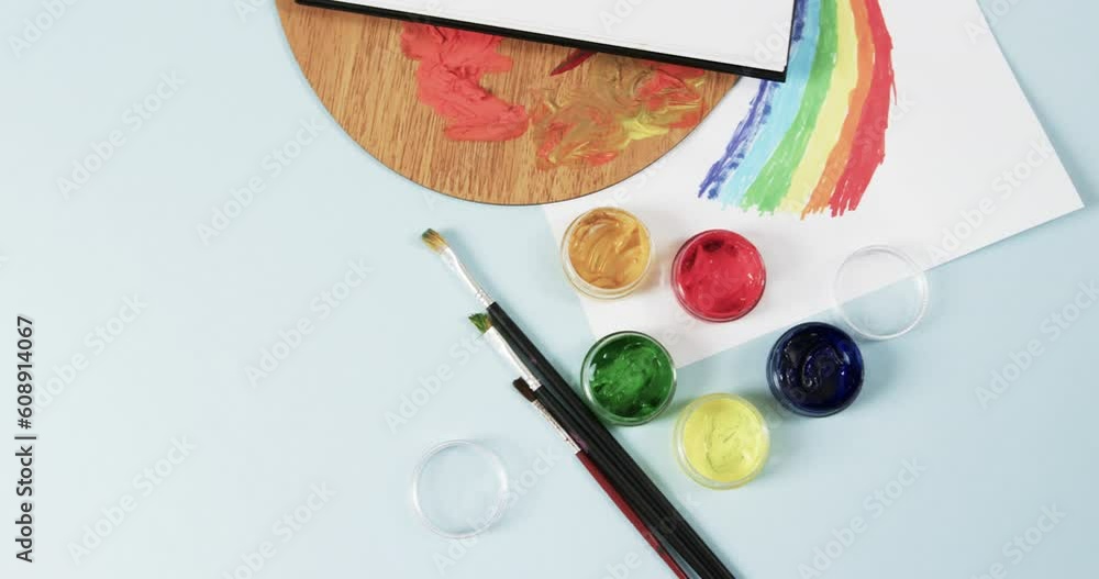 Poster overhead view of notebook, brushes and paints on blue background with copy space, in slow motion
