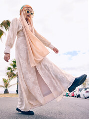 Woman, muslim fashion and street in low angle portrait with gen z aesthetic, beauty and walking in city. Young islamic girl, student and clothes with sunglasses, freedom and travel on road in Dubai