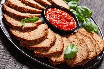 italian meatloaf cut in slices on black plate