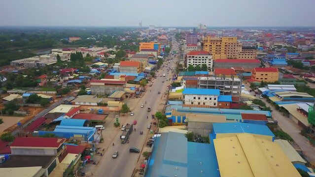 Aerial cinematic drone Poi Pet Cambodia Thailand border rickshaw motorbike trucks cars traffic on roads casino township poor slums colorful rooftops train tracks daytime cloudy smog slowly circling