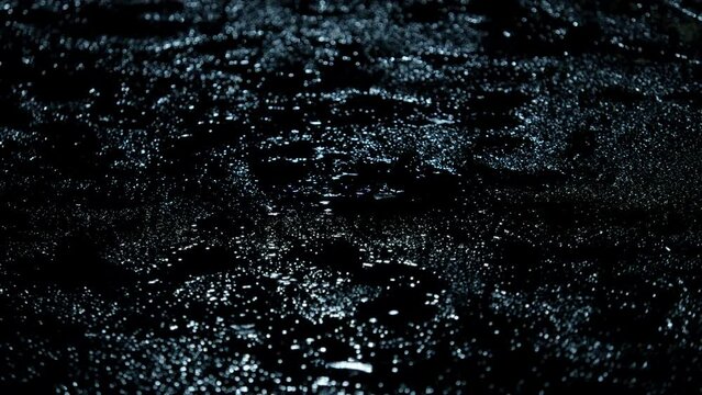 Closeup of rain drops falling on puddle with lights reflection on city sidewalk, Rain drop with street lights at night, Weather or environment	