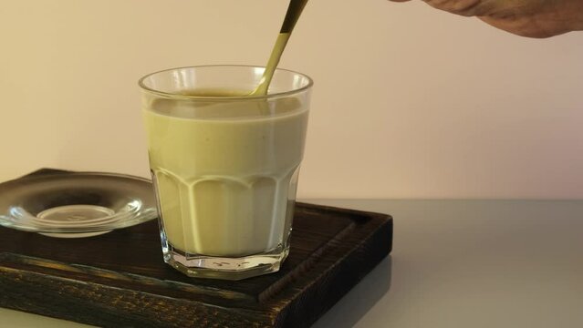 Man stirs thick tea with milk and spaces with spoon. Karak tea or Masala chai. Popular Indian warming drink.