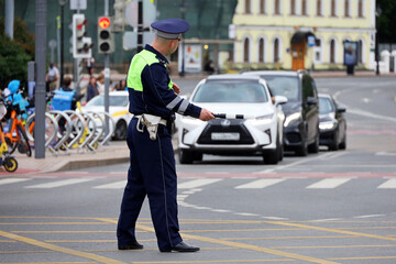 Traffic police officer standing with rod on a road on cars background. Policeman patrol the city...