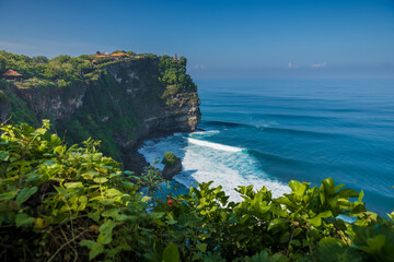 Scenic cliff and ocean with waves in Uluwatu, Bali. Popular place with balinese temple