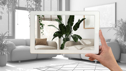 Augmented reality concept. Hand holding tablet with AR application used to simulate furniture and design products in total white background, urban jungle living room
