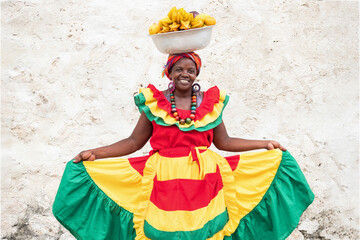 Cheerful fresh fruit street vendor aka Palenquera in the Old Town of Cartagena, Colombia.  - obrazy, fototapety, plakaty