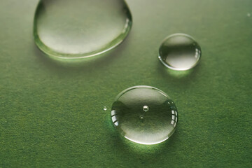 Three drops of liquid on a green background.