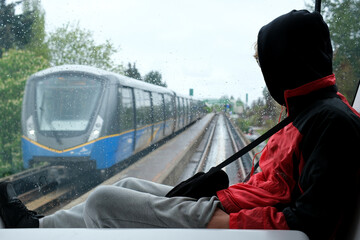 teenager person sitting on windshield of skytrain looking at moving train at him teenage life mistakes of youth forbidden place not following rules a fine to misbehave badly relaxation pleasure dream