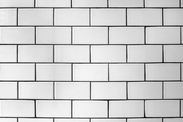 The textured wall is lined offset with white glossy ceramic tiles.
