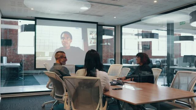 Group of diverse professionals having an online meeting in a boardroom. Business team discussing a new partnership opportunity with remote associates as they connect over a video conference.