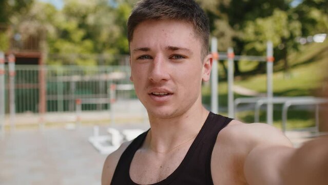 POV selfie of athletic bodybuilder man records video lessons on camera, blog vlog for social media. Young guy on playground talking about sports, health, fitness routine, workout. Strength motivation