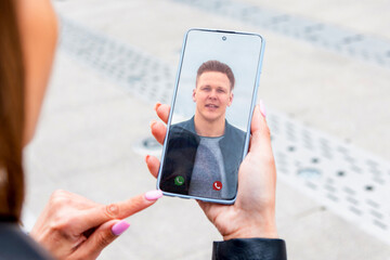 A young couple talking to each other via online video chat.The girl is holding a smart phone while...