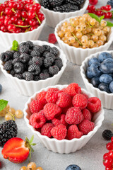 Various fresh berries in bowls on a gray concrete background. Healthy food concept.