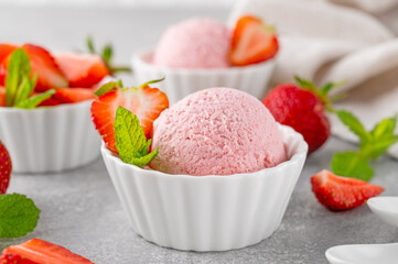 Strawberry ice cream with fresh berries in a bowl on a gray concrete background. Selective focus