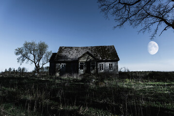Fototapeta premium Spooky scene of haunted house and moon.Old mystic building at dead tree.Horror Halloween concept.Toned.