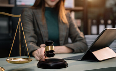 Justice and law concept. Female judge in a courtroom the gavel, working with tablet computer on table in sun light.