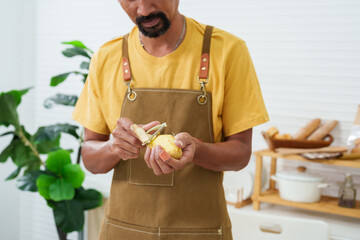 Man chef holding kitchen utensil called fruit vegetable peeler, man chef using paring knife peel...