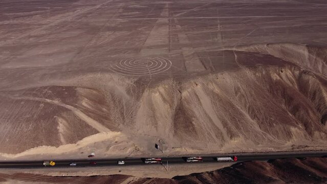 Aerial video of the Nazca Lines. Drone flies forward above the desert plateau tilting camera up. Below can be seen many long linear geoglyphs and a spiral symbol. Located in Nazca, Peru.