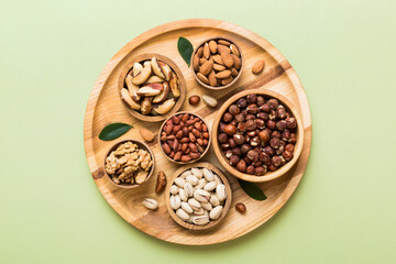 mixed nuts in wooden bowl. Mix of various nuts on colored background. pistachios, cashews, walnuts, hazelnuts, peanuts and brazil nuts