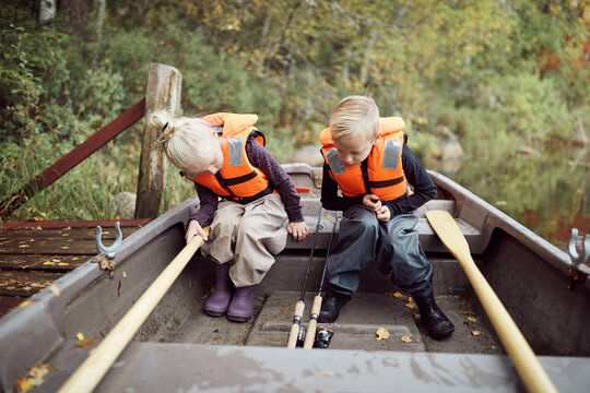 Cute little brother and sister going fishing in a canoe