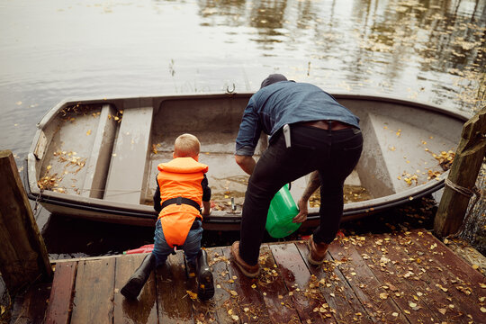 Father and little son baling water from their fishing boat