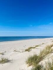 Fototapeta na wymiar White sandy dunes with blue sea background, blue sea horizon, wild beach, no people