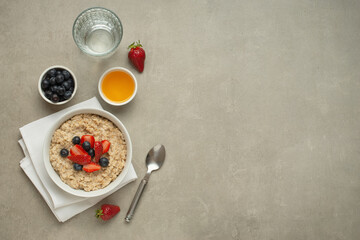 Oatmeal with berries and honey on a gray table