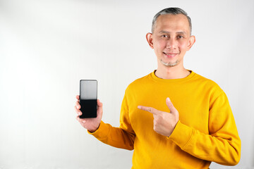 Portrait of Asian man with yellow tshirt holding the cellphone, showing the application. 
