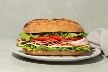 Sandwich with mortadella, cheese and tomatoes on a gray table