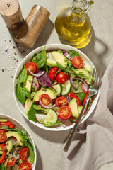 Vegetable salad with tomatoes, avocado and cucumber on a gray background