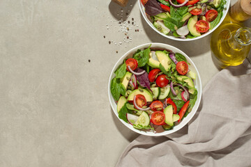 Vegetable salad with tomatoes, avocado and cucumber on a gray background