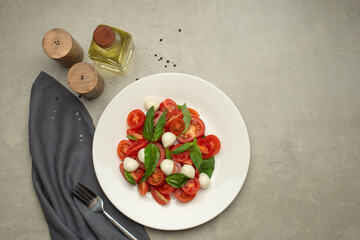 Salad with tomatoes, mozzarella and basil on a gray background