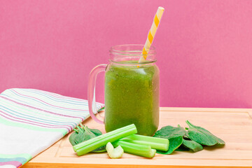 Fresh Green Smoothie of Apple, Celery, and Spinach in Glass Smoothie Jar with Yellow Cocktail Straw...