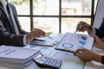 Meet with colleagues to discuss sales analysis in financial reports with graph papers. Financial accounting and business strategy planning related to sales analysis in company marketing reports.