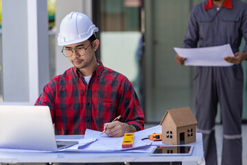 Construction site engineers, two businessmen Engineering objects in workplace with interacting partners, contractors and architects looking at plans on laptop and talk about working on the project