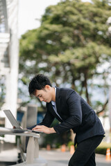 Confident Asian man with a smile standing holding notepad and tablet at the modern office..