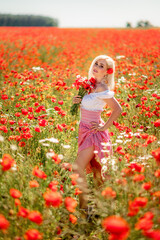 blonde woman in a poppy field with daisies. A girl with a bouquet of red and white flowers