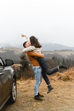 a couple in the autumn time having fun traveling. a man holds a girlfriend in his arms. happy couple on high ground. couples autumn vacation