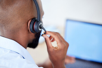 Consultant, back view of black man with headset and laptop at his desk for support. Telemarketing...